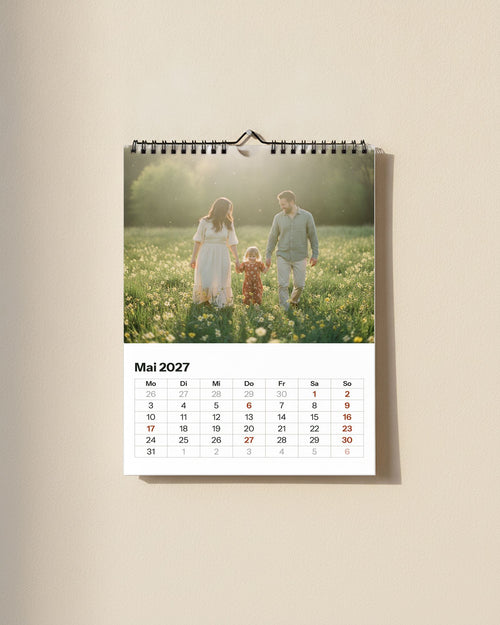 Wandkalender A4 hoch, frontal: Familienfoto oben, darunter das Kalendarium Mai 2027 mit Wochentagen Mo bis So, schwarze Wire-O-Bindung